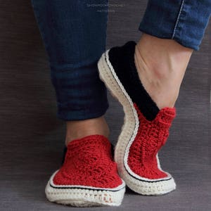 May include: A pair of red, black, and white crocheted slippers. The slippers have a white trim and a black stripe around the top.