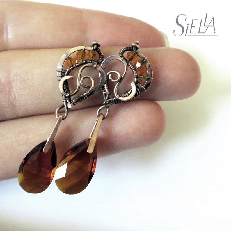 Peut inclure: Boucles d'oreilles en fil de cuivre avec un motif en spirale et des cristaux ambr&eacute;s en forme de goutte.