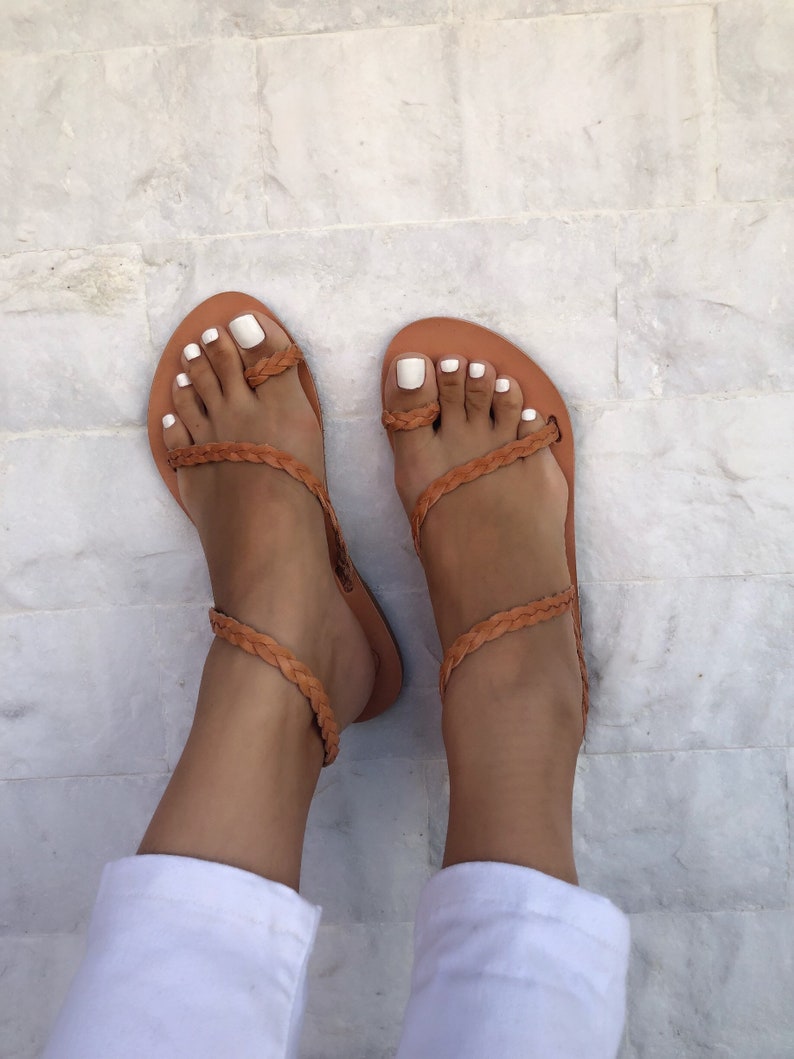 Puede incluir: Un par de sandalias de cuero marr&oacute;n con correas trenzadas. Las sandalias tienen un dise&ntilde;o sencillo y son perfectas para el verano.