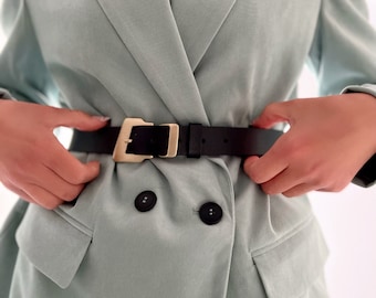 May include: A light green blazer with a double breasted closure and black belt with a gold buckle.