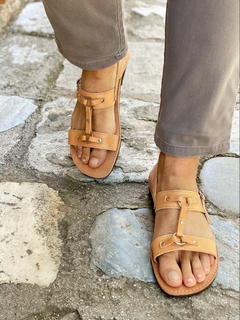 Puede incluir: Un par de sandalias de cuero marr&oacute;n con m&uacute;ltiples correas y hebillas. Las sandalias tienen la punta cerrada y una suela gruesa.