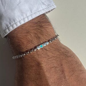 Könnte beinhalten: Ein silbernes Kettenarmband mit einer Reihe kleiner türkisfarbener und weißer Steine.