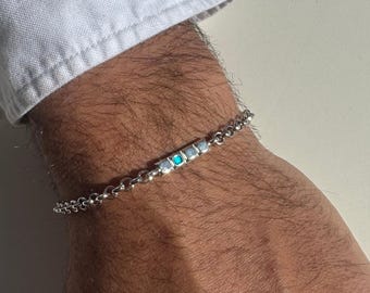 May include: A silver chain bracelet with a row of small turquoise and white stones.