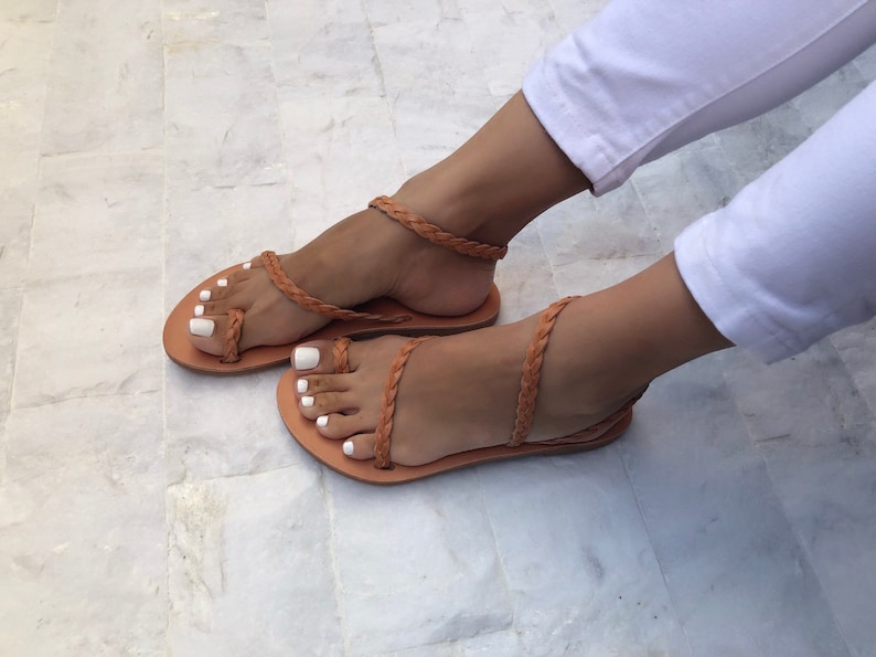 Puede incluir: Un par de sandalias de cuero marr&oacute;n con tiras trenzadas. Las sandalias tienen un dise&ntilde;o sencillo y son perfectas para el verano.