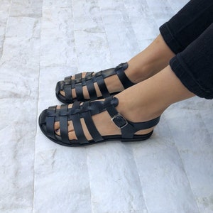 Op de afbeelding: Zwarte leren sandalen met een kooi-ontwerp en een gespsluiting.