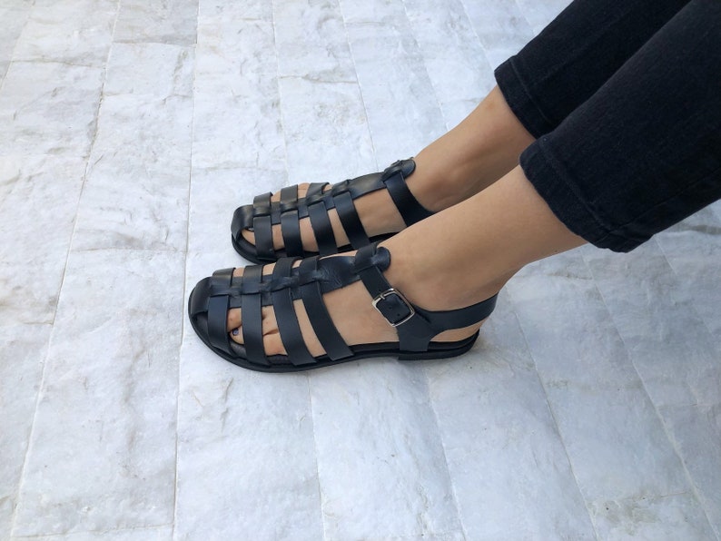 Op de afbeelding: Zwarte leren sandalen met een kooi-ontwerp en een gespsluiting.