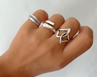 Puede incluir: Un conjunto de tres anillos de plata. Los anillos son de diferentes estilos, uno es una banda simple, otro es una banda retorcida y otro es un diseño geométrico.