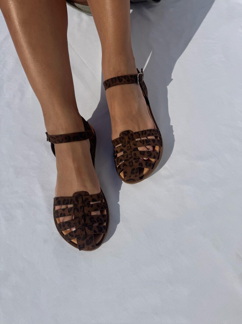 May include: A pair of brown sandals with a leopard print design. The sandals have a caged design and ankle straps.