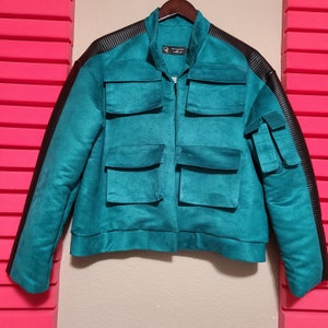 May include: A teal blue jacket with black accents and multiple pockets. The jacket has a zipper closure and a stand-up collar.