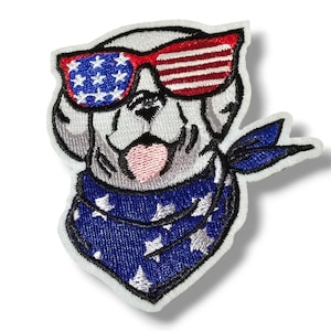 Peut inclure: Patch brodé thermocollant représentant un chien portant des lunettes de soleil rouge, blanc et bleu et un bandana à étoiles. Le chien est blanc avec une langue rose qui sort.