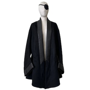 Puede incluir: Una bata de terciopelo negro con solapa de satén y mangas largas. La bata tiene un cuello chal y cierre de corbata.