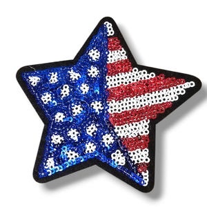 Puede incluir: Un parche de lentejuelas en forma de estrella con los colores de la bandera estadounidense. El lado izquierdo es azul con lentejuelas blancas, y el lado derecho tiene rayas rojas y blancas. El parche tiene un borde negro.