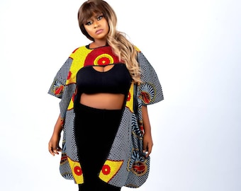 May include: A woman wearing a black crop top and black leggings with a colorful patterned kimono-style top. The top has a yellow, red, and blue geometric pattern.