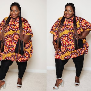 以下が含まれることがあります： 黄色、赤、黒の模様のシャツを着た女性。黒いパンツと銀色のヒールを履いています。シャツはゆったりとしたルーズフィットで、前面に黒いポケットが2つ付いています。