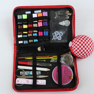 May include: A red sewing kit containing a selection of colourful threads, needles, buttons and other sewing essentials. The kit is open, revealing its contents.