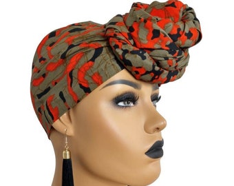 May include: A green and red patterned head wrap with a large knot on top. The wrap is worn by a mannequin with black tassel earrings.