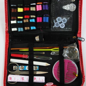 May include: A red zippered sewing kit containing a range of sewing supplies, including thread, needles, pins, buttons, a thimble, a tape measure, and a pincushion.