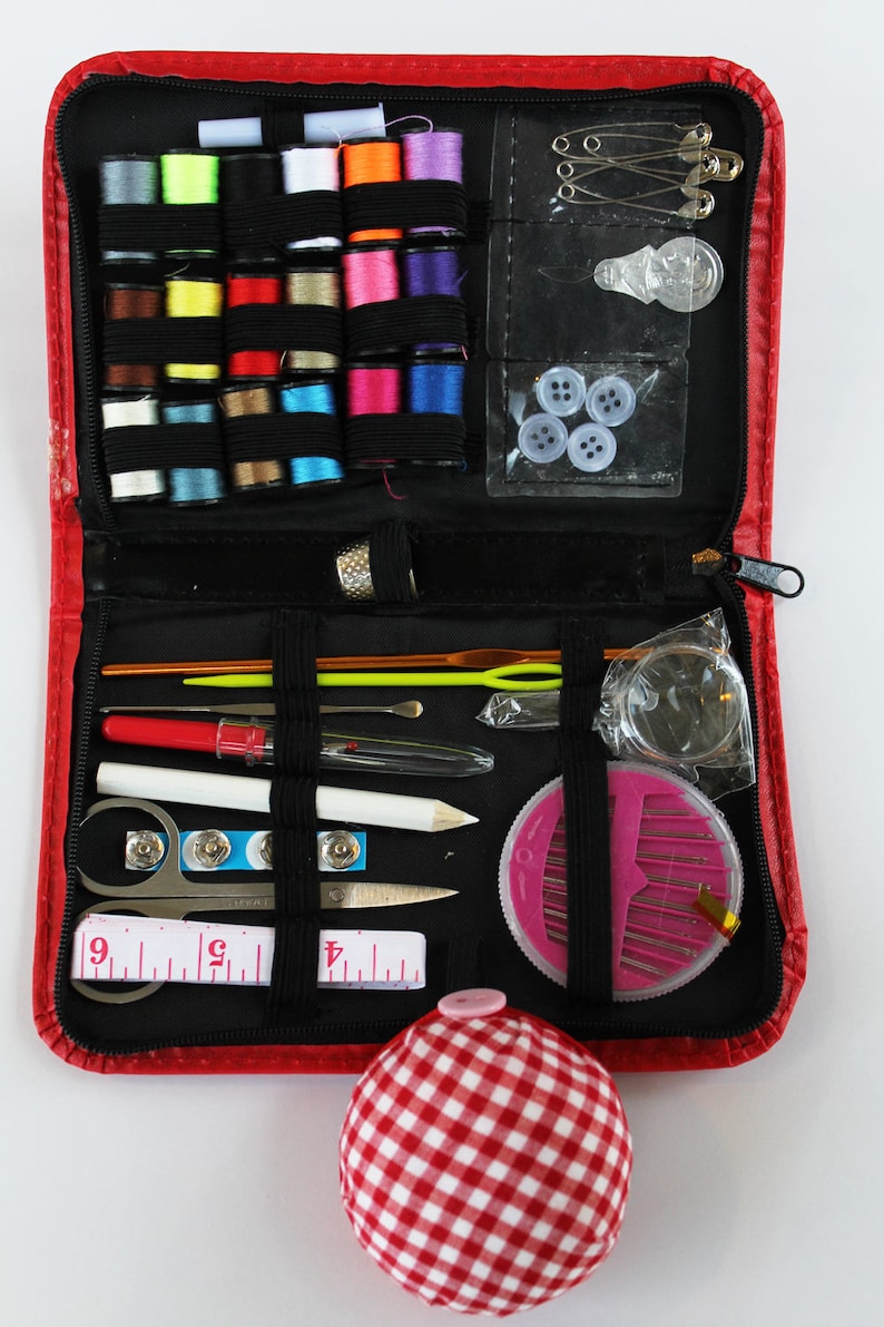 May include: A red zippered sewing kit containing a range of sewing supplies, including thread, needles, pins, buttons, a thimble, a tape measure, and a pincushion.