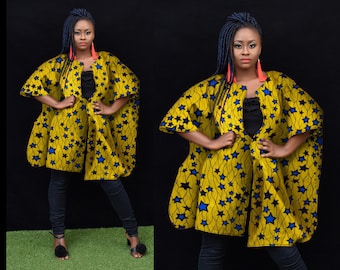 May include: A yellow and blue patterned cape with a black star design. The cape has a V-neck and long sleeves. The model is wearing black pants and black shoes.
