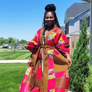 May include: A long, red and brown patterned robe with a white sash. The robe has a V-neck and long sleeves. The pattern is a mix of geometric shapes and floral designs.