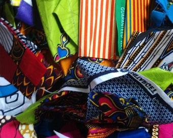 May include: A pile of colorful fabric scraps with various patterns, including stripes, polka dots, and floral designs. The fabric is a mix of cotton and silk, and some of the scraps have the words "Guaranteed" and "Holland" printed on them.