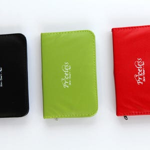 May include: Three card holders in different colours with the word "priceless" printed on them. The card holders are black, green and red.