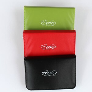 May include: Three small, rectangular cases stacked on top of each other. The top case is green, the middle case is red, and the bottom case is black. Each case has the word "Priceless" printed on the front in white lettering.