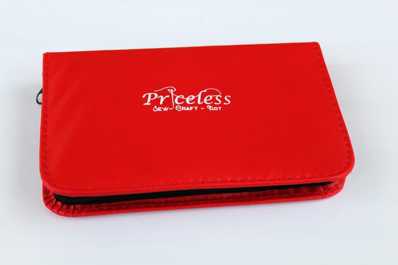 May include: Red leather case with a black zipper and the text "Priceless Sew-Craft-Art" in white.