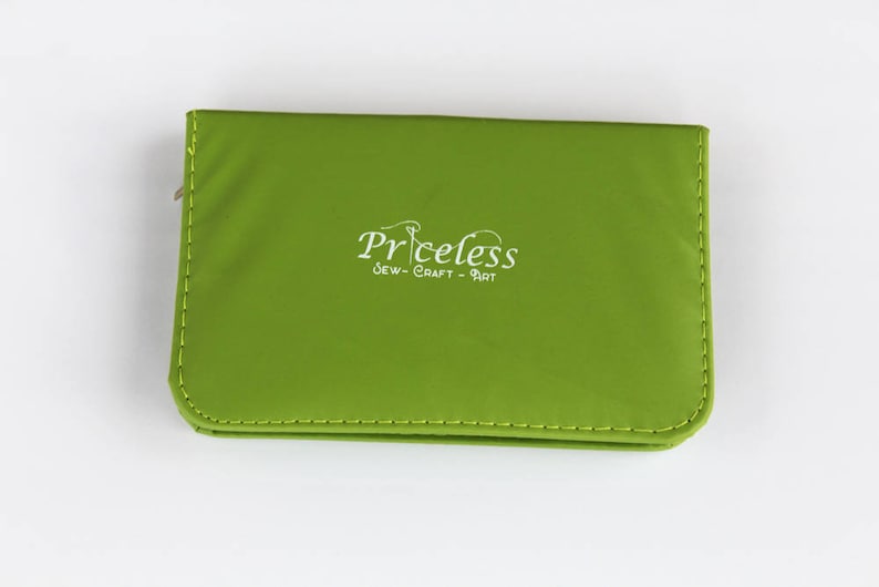 May include: A green zippered pouch with the text "Priceless Sew-Craft-Art" in white.