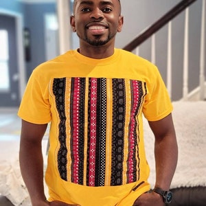 May include: A yellow t-shirt with a black, red, and white patterned design on the front.