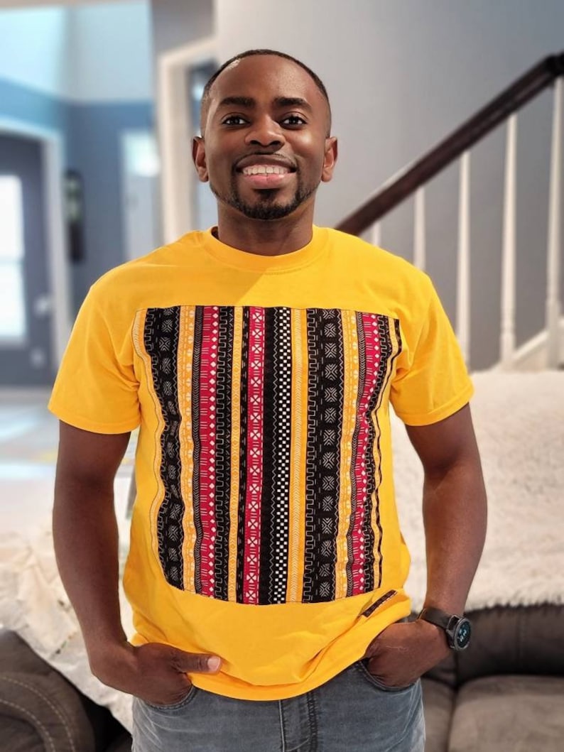 May include: A yellow t-shirt with a black, red, and white patterned design on the front.