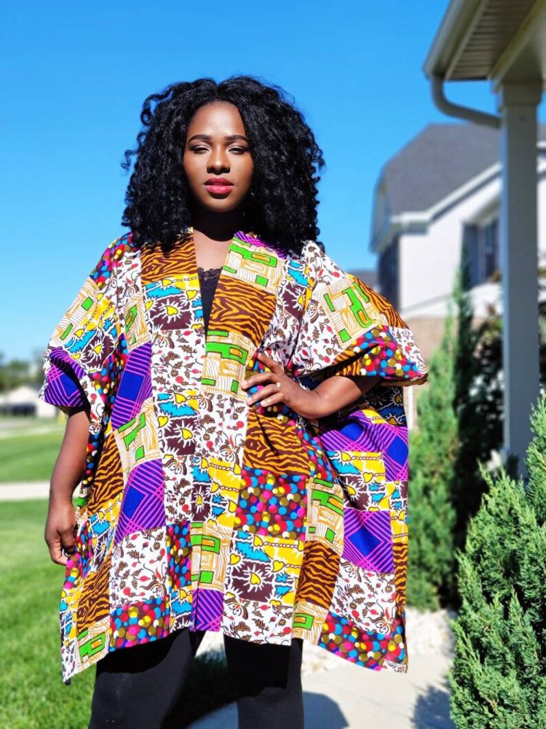 May include: A colourful patchwork kimono with a mix of patterns in purple, yellow, and brown. The garment has wide sleeves and a relaxed fit. The kimono is ideal for layering and features a variety of geometric and floral designs.