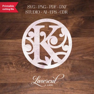 May include: A white, laser-cut monogram initial "K" with decorative flourishes. The letter is in a circle and the design is on a wood background. The text "Lasercut Lace" is below the circle.