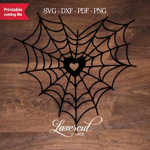 May include: A black spiderweb design in the shape of a heart with a small heart in the center. The design is on a wood background with the text "Lasercut Lace" below it.
