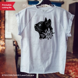 May include: A white t-shirt with a black silhouette of a cat's head with flowers around its neck. The text "Lasercut Lace" is printed on the bottom of the shirt.
