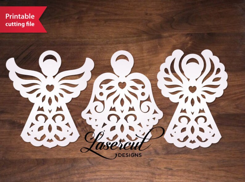 May include: Three white paper cut-out angel ornaments with intricate designs. Each angel has a heart in the center of its chest and wings with a decorative pattern.