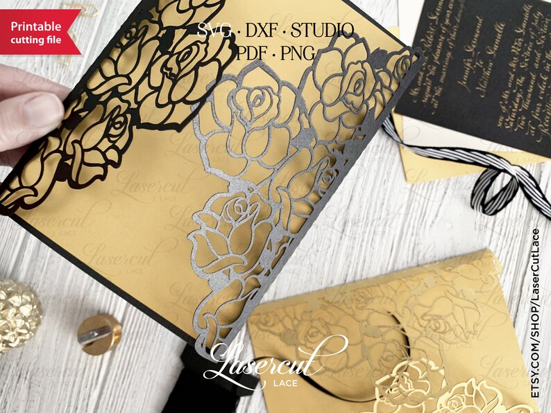 May include: Black laser cut rose design for a wedding invitation. The design is intricate and features a delicate floral pattern. The invitation is printed on gold cardstock.