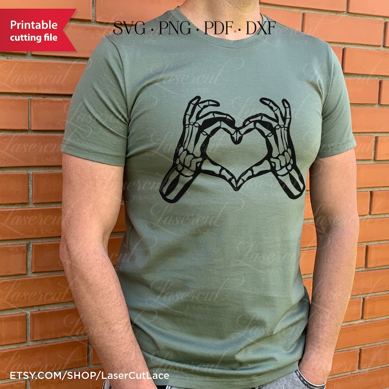 May include: A green t-shirt featuring a black skeleton hand design forming a heart shape. The text "SVG.PNG.PDF.DXF" is printed above the design. The text "Etsy.com/shop/LaserCutLace" is printed below the design.