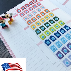 May include: A planner page with a set of colorful washing machine stickers. The stickers are arranged in rows of different colors, starting with red and ending with purple. The stickers are on a white page with pink lines.