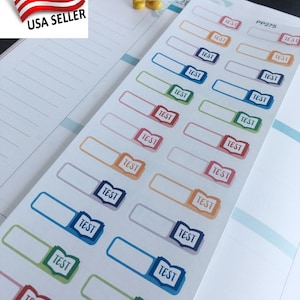 May include: A sheet of colorful planner stickers with the word "TEST" in a book icon. The stickers are in various colors, including pink, blue, green, and orange. The sheet is labeled "PP275".