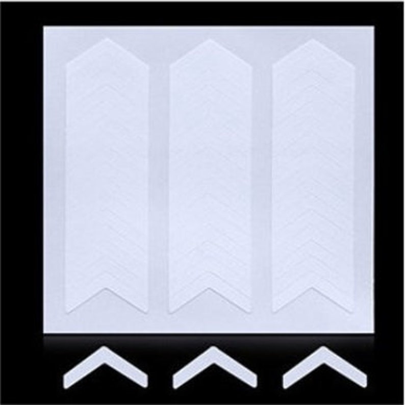 May include: Three white adhesive strips with a chevron pattern. Each strip has a pointed end and a rounded end. The strips are designed to be used for crafts, scrapbooking, or other projects.