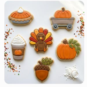 Peut inclure: Un ensemble de six biscuits sur le thème de Thanksgiving comprenant une tarte à la citrouille, un chariot avec une citrouille, un café avec de la crème fouettée, une dinde, une citrouille avec des feuilles et un gland. Le texte indique Thanksgiving Set A - Set of 6 et *Digital STL Files ONLY*.