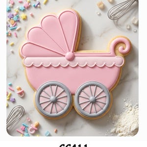 May include: A sugar cookie shaped like a baby carriage with pink icing, a scalloped edge, and two grey wheels. The cookie is surrounded by colorful sprinkles, small pacifier-shaped candies, and two metal whisks. The text CC411 is printed below.