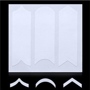 May include: Three white nail guide stickers with different shapes: a straight edge, a curved edge, and a pointed edge. The stickers are designed to help create perfect nail lines.