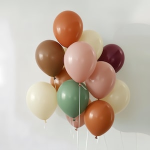 May include: A cluster of colorful balloons in various shades of brown, pink, green, and cream. The balloons are tied together with white string, creating a festive and celebratory arrangement. Perfect for a birthday or party.