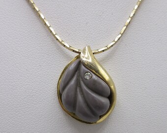 May include: A gold chain necklace with a pendant featuring a carved grey leaf with a small diamond accent.