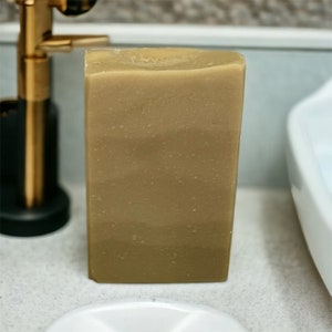 May include: A rectangular bar of brown soap with a speckled texture. The soap is sitting on a white countertop.