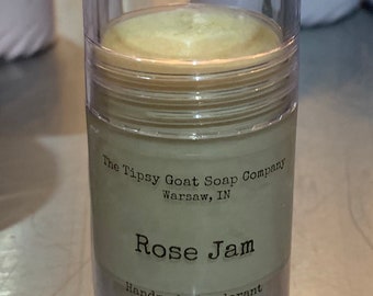 May include: A clear plastic container with a white label that reads "The Tipsy Goat Soap Company Warsaw, IN Rose Jam Handmade Deodorant 1.25oz (35g)". The container is filled with a light yellow deodorant.