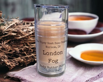May include: A clear plastic tube containing a beige body butter stick. The label reads "London Fog Body Butter Stick" and "The Tipsy Goat Soap Company, Warsaw, IN." The product is 1.25oz (35g).