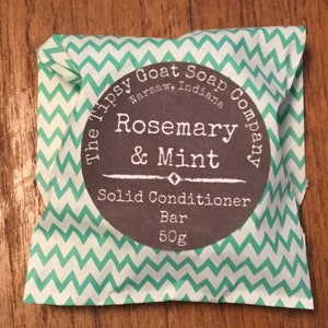 May include: A white and green chevron patterned paper wrapper with a round label that reads "The Tipsy Goat Soap Company, Warsaw, Indiana". The label also says "Rosemary & Mint Solid Conditioner Bar 50g".